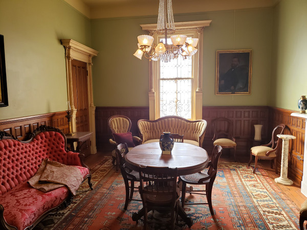 Elegant dining room with chandelier, wooden paneling, and patterned rug.