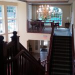 Grand interior staircase overlooking a pool area with large windows.