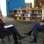 George W. Bush and a man in a suit interview in a library-like setting.