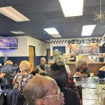 Group of people gathered in a casual dining area, socializing and eating.