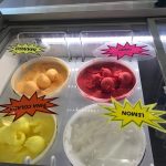 Assortment of colorful ice cream flavors in a refrigerated display case.