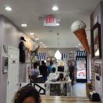 Interior view of a modern retail space with artwork, counter area, and exit sign.