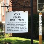 Historical marker commemorating 250 years of Quaker meetinghouse in a brick setting.