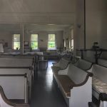 Empty church interior with rows of pews and high ceilings.