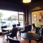 Dark interior restaurant with leather seating overlooking a street scene.