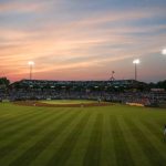 Baseball stadium at sunset with a wide view of the field and grandstands.