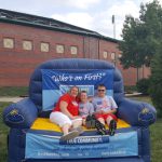 Family posing on a blue inflatable bounce house with "Who's on First?" banner.