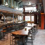 Modern, industrial bar and restaurant interior with a long wooden counter.