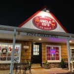 Night view of Uncle Ed's Ice Cream shop with "Fine Chocolates" sign.