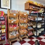 Wooden tiered displays of colorful candies and snacks in a retail setting.