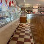 Bakery display case with festive decorations and checkered floor in a shop interior.