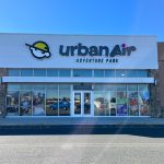 Urban Air Adventure Park storefront with large windows and blue sky backdrop.