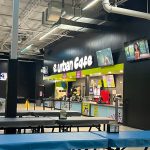 Urban Cafe interior with black walls, modern seating, and digital menu boards.