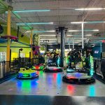 Arcade racing game setup with colorful, illuminated karts and track in a modern entertainment venue.
