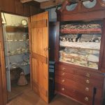 Wooden cabinet with antique dresser and glass display case in a rustic interior.