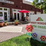 West Windsor Arts Center sign next to a brick building with outdoor seating.