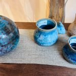 Ceramic pottery collection: blue vases and mugs displayed on a wooden surface.