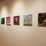 Gallery wall display of various abstract and still life paintings.