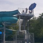 Water park slide tower with people enjoying the slides under a cloudy sky.