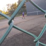Soccer player in action on a field with a large dark goal backdrop.