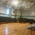 Large, empty auditorium with wooden floor and tiered seating for events or performances.