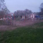 Foggy park playground with colorful climbing structures under a gray sky.