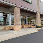 Exterior view of a modern grocery store with stone columns and large windows.
