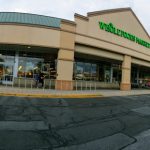 Whole Foods Market exterior with large windows and tan facade under an overcast sky.