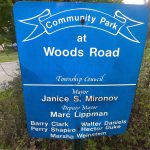 Blue sign for Community Park at Woods Road, listing Township Council members.