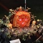 Carved pumpkin centerpiece display at a nighttime outdoor event.