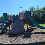 Colorful playground equipment with slides and climbing structures under a bright blue sky.